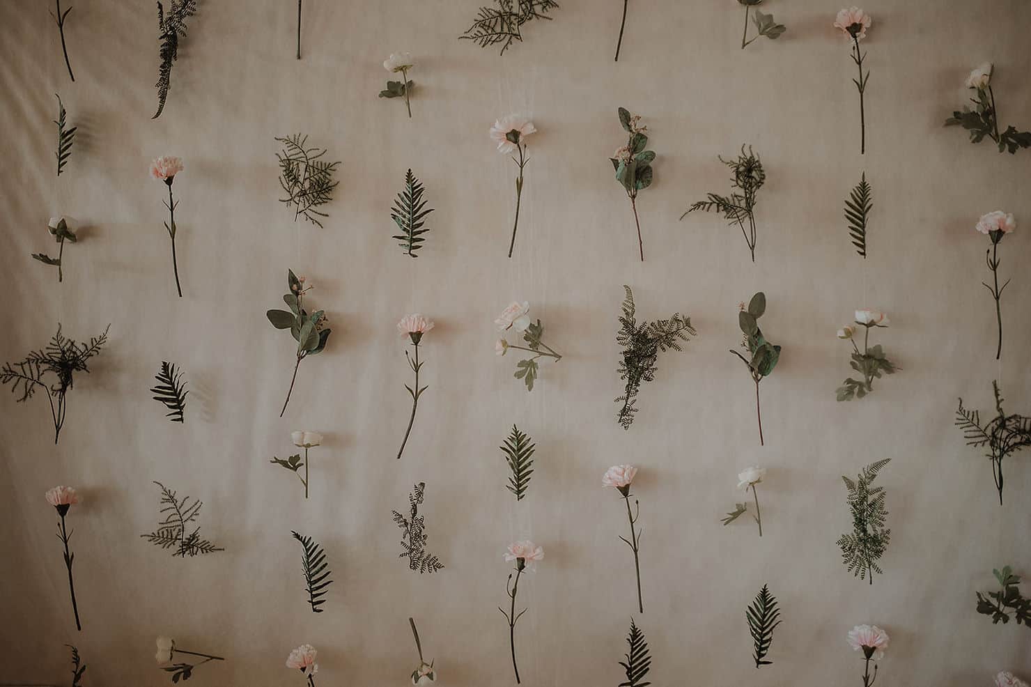 Vegg pyntet med blomster og bregner til bryllupet